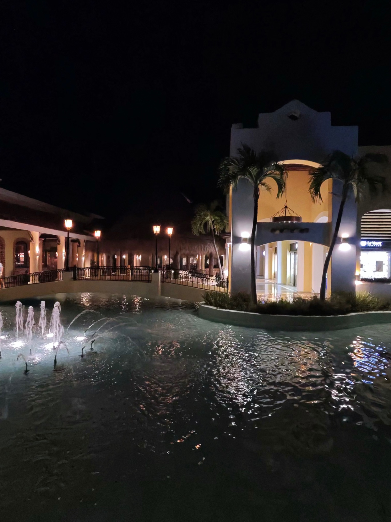 Illuminated fountain and colonial-style plaza at night