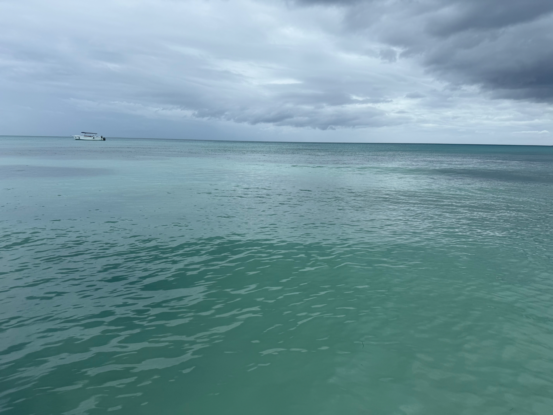 Calm turquoise water with a small boat on the horizon in Punta Cana