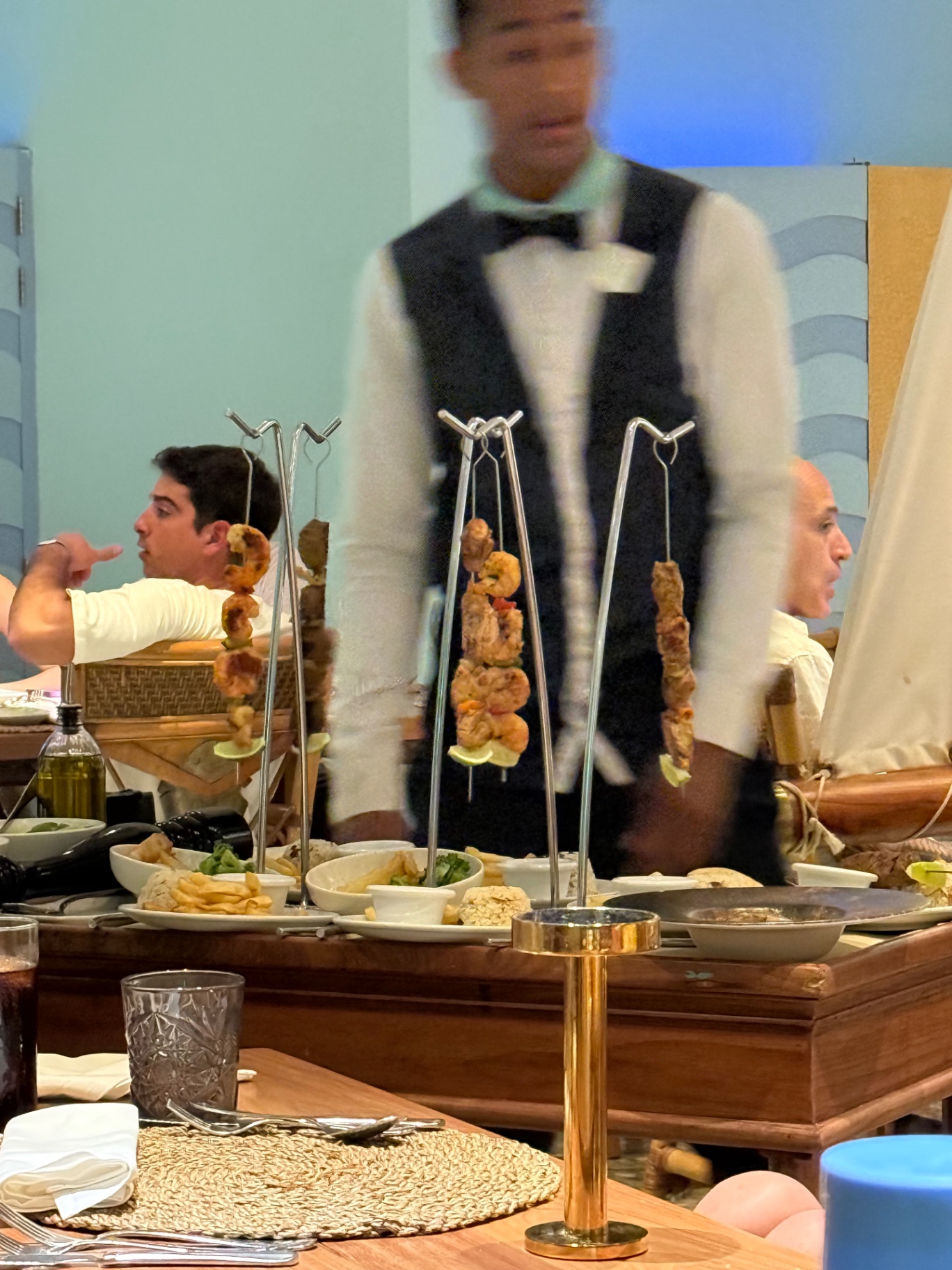 Tableside skewers of shrimp, chicken and beef served by a waiter in a bow tie