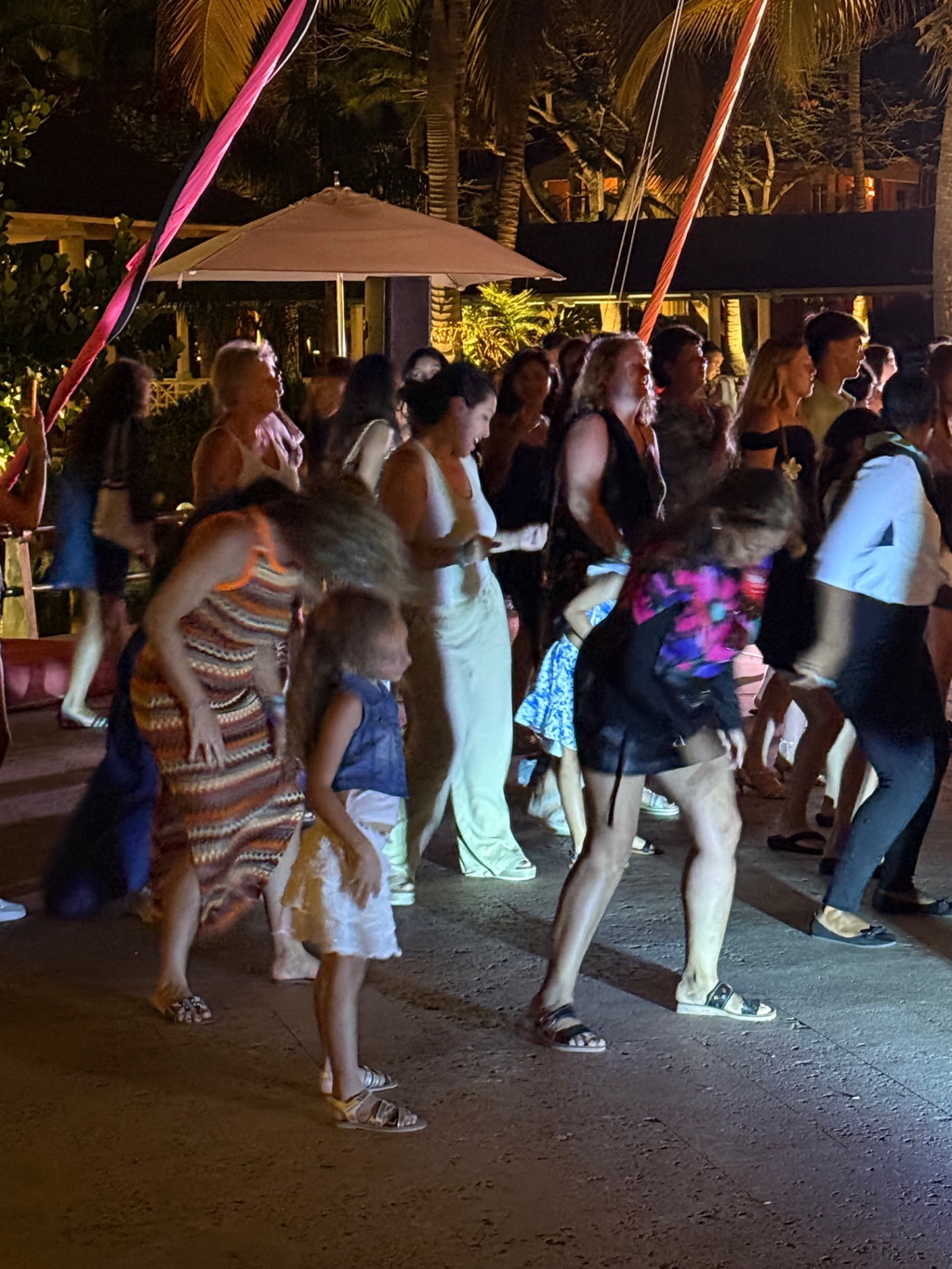 Guests dancing at a nighttime resort party under palm trees