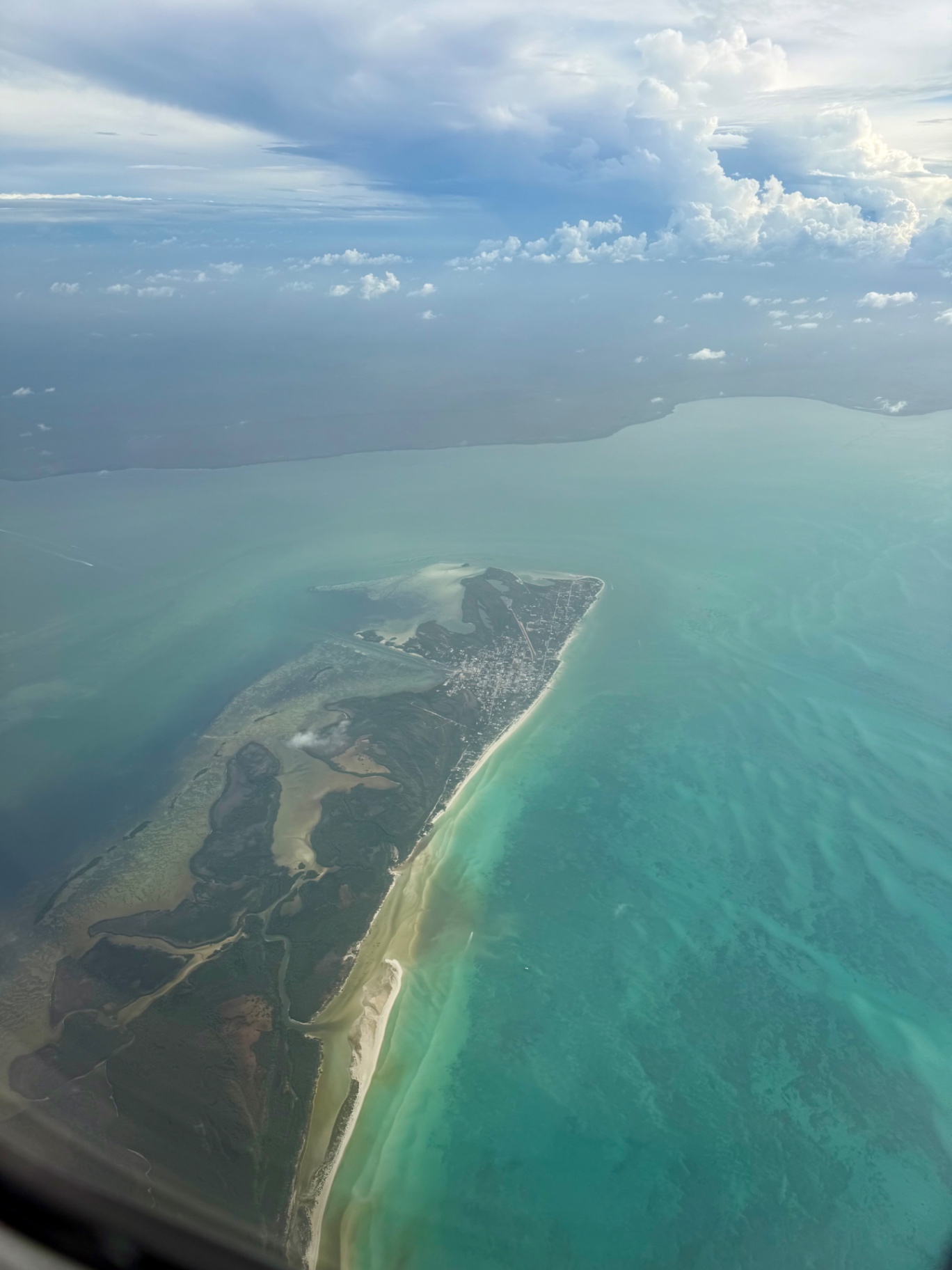 Aerial view of an island with turquoise water flying into the Riviera Maya