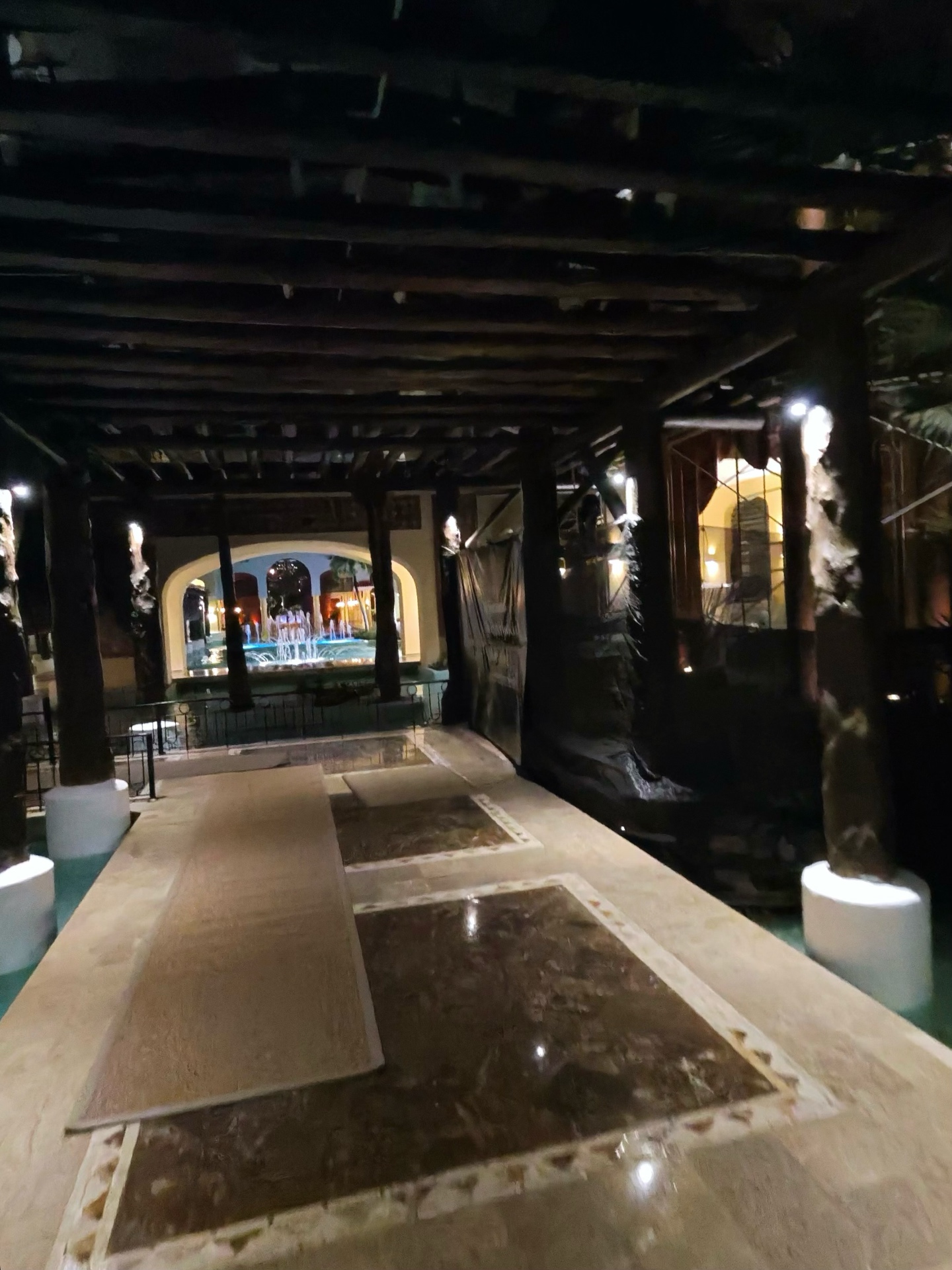 Wooden colonial walkway looking toward lit fountain courtyard